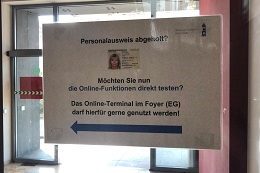 Hinweisschilder machen an geeigneten Stellen die neuen Inhaber eines Personalausweises auf das Terminal aufmerksam.